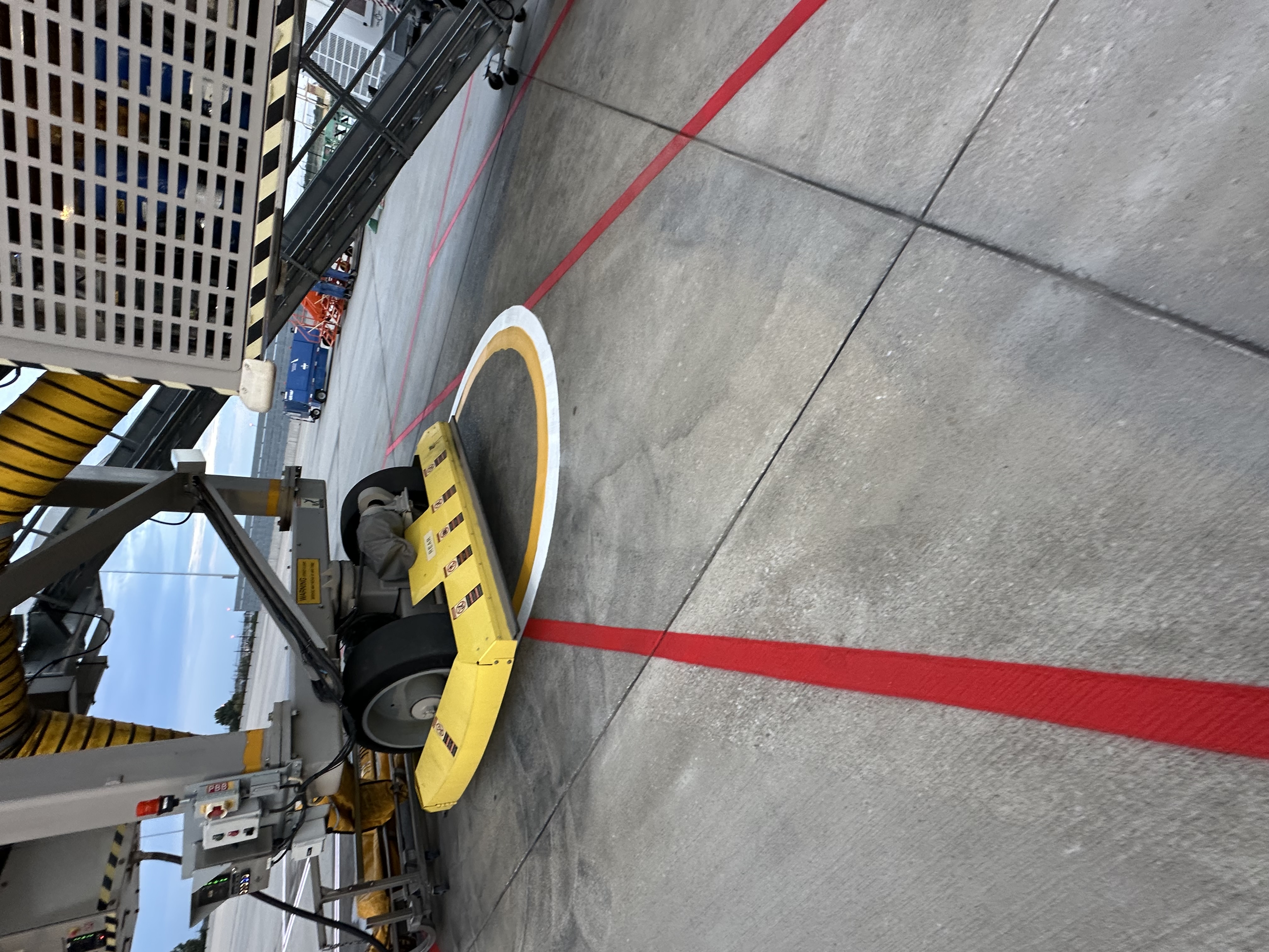Red safety boundaries and a painted clearance circle beneath a jet bridge